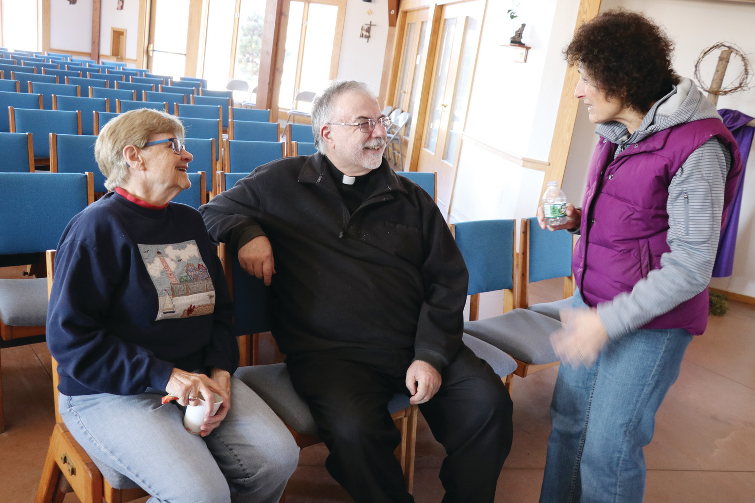 Father Paul Desmarais speaks with parishioners Carolyn Craig and Gloria Sloan about the benefits of the new parish center.